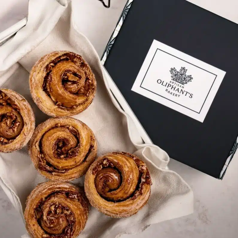Buttery brown butter pecan bun in a small bakery box, featuring a rich, nutty filling for a perfect treat